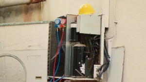 HVAC technician inspecting the parts of an air conditioner, including the compressor, condenser coil, wiring, and refrigerant lines