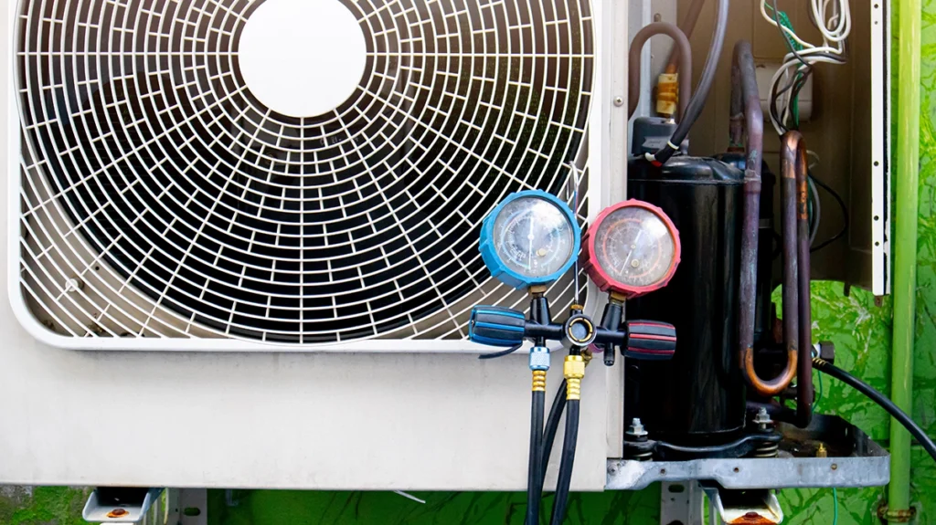 Technician gauges connected to an outdoor AC unit during service, showing equipment associated with R454B refrigerant and modern home cooling systems